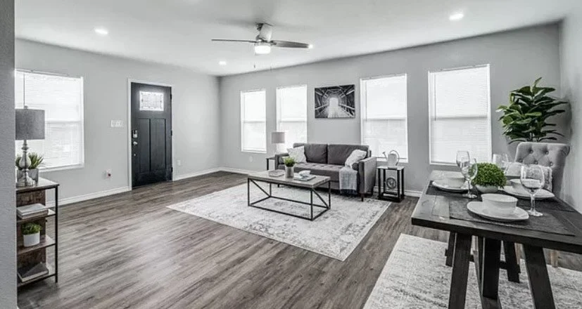 Renovated living room with new flooring, ceiling fan and black front door